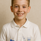 Young boy wearing a white polo shirt with logos on a beige background - showing the TeeMemento cricket motif and personalisation