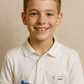 Young boy wearing a white polo shirt with logos on a beige background showcasing a TeeMemento product