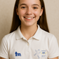 Young girl wearing a white polo shirt with logos on a beige background - showing the TeeMemento cricket motif and personalisation