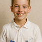 Young boy wearing a white polo shirt with logos on a beige background - showing the TeeMemento cricket motif and personalisation