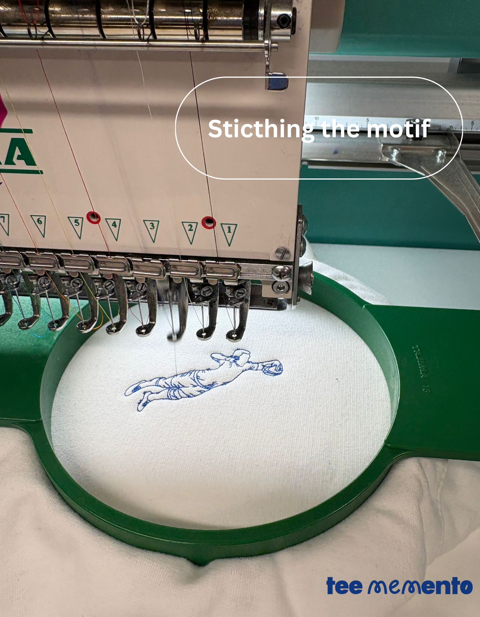 Embroidery machine stitching a design on fabric with 'teememento' branding.
