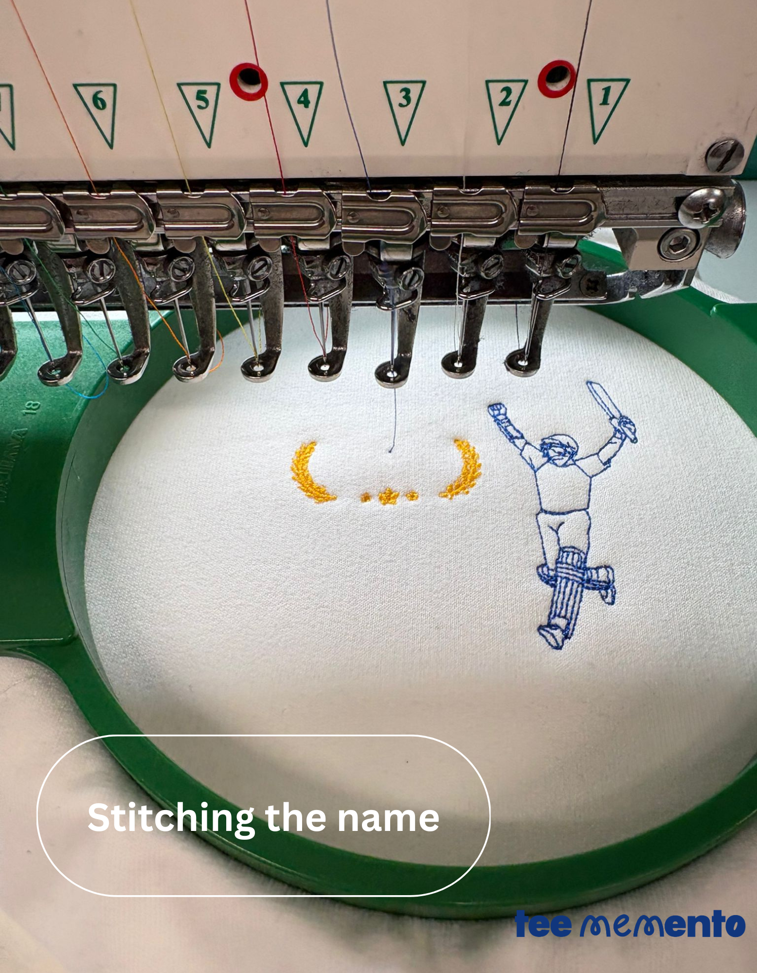 Embroidery machine in action with a design being stitched on fabric, featuring the brand 'TeeMemento'.