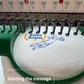 Embroidery machine with a partially completed design on fabric, featuring the brand 'Kiran Burgess' and 'teememento'.