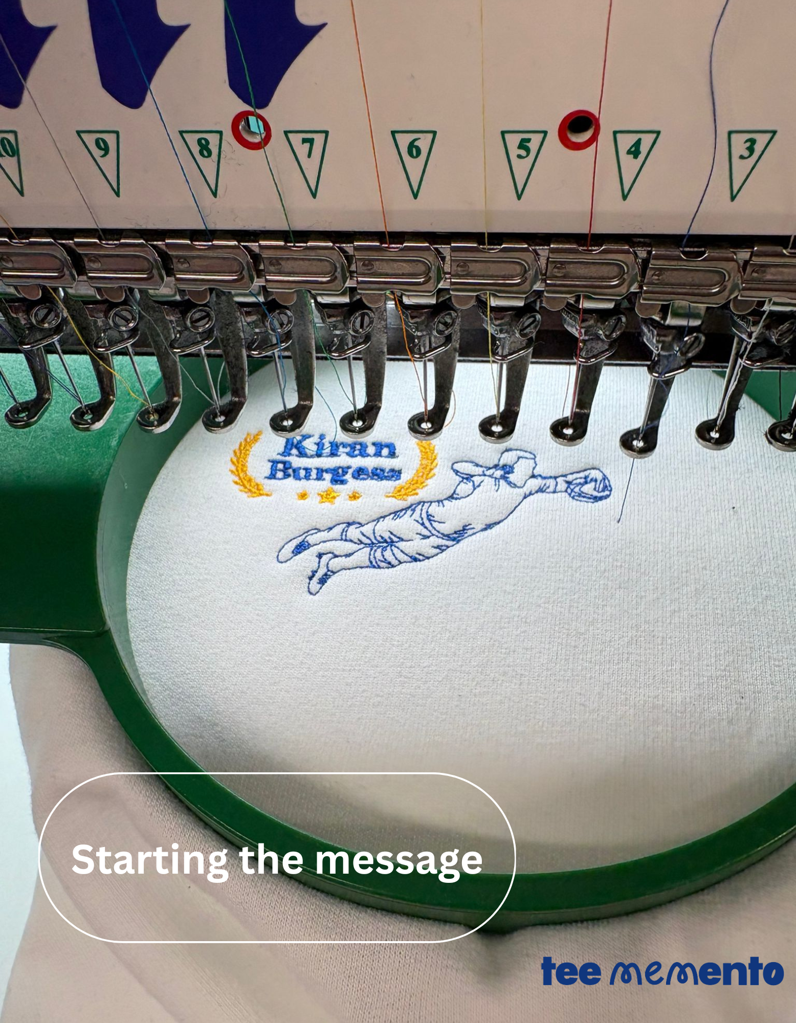 Embroidery machine with a partially completed design on fabric, featuring the brand 'Kiran Burgess' and 'teememento'.